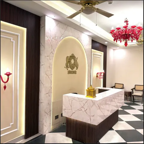 Marble reception desk beneath a red glass chandelier